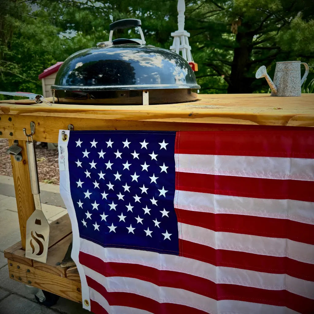 American Flag on Grill Station | Fine Line Flag | Patriotic Backyard BBQ Setup | Outdoor Flag Display Ideas | Decorate Your Grill Area with Old Glory | Backyard Flag Inspiration | Celebrate with the Stars and Stripes | Flag Display for Cookouts and Holidays | Patriotic Outdoor Décor | Flag Placement for Summer BBQs | Hosting with American Pride | Red, White & Blue Backyard Vibes