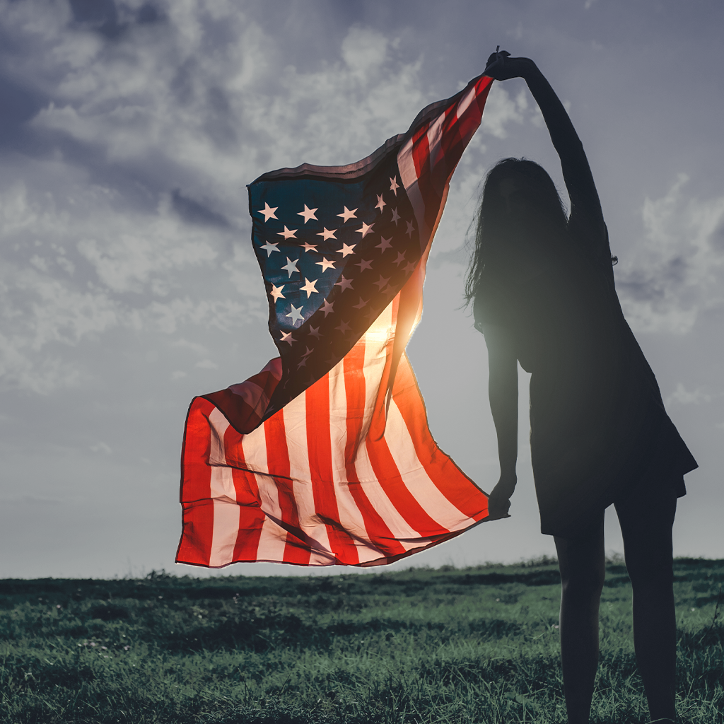 Girl holding American flag sunset