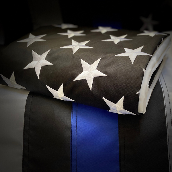 Close-up of embroidered white stars on the black field of a folded Thin Blue Line flag